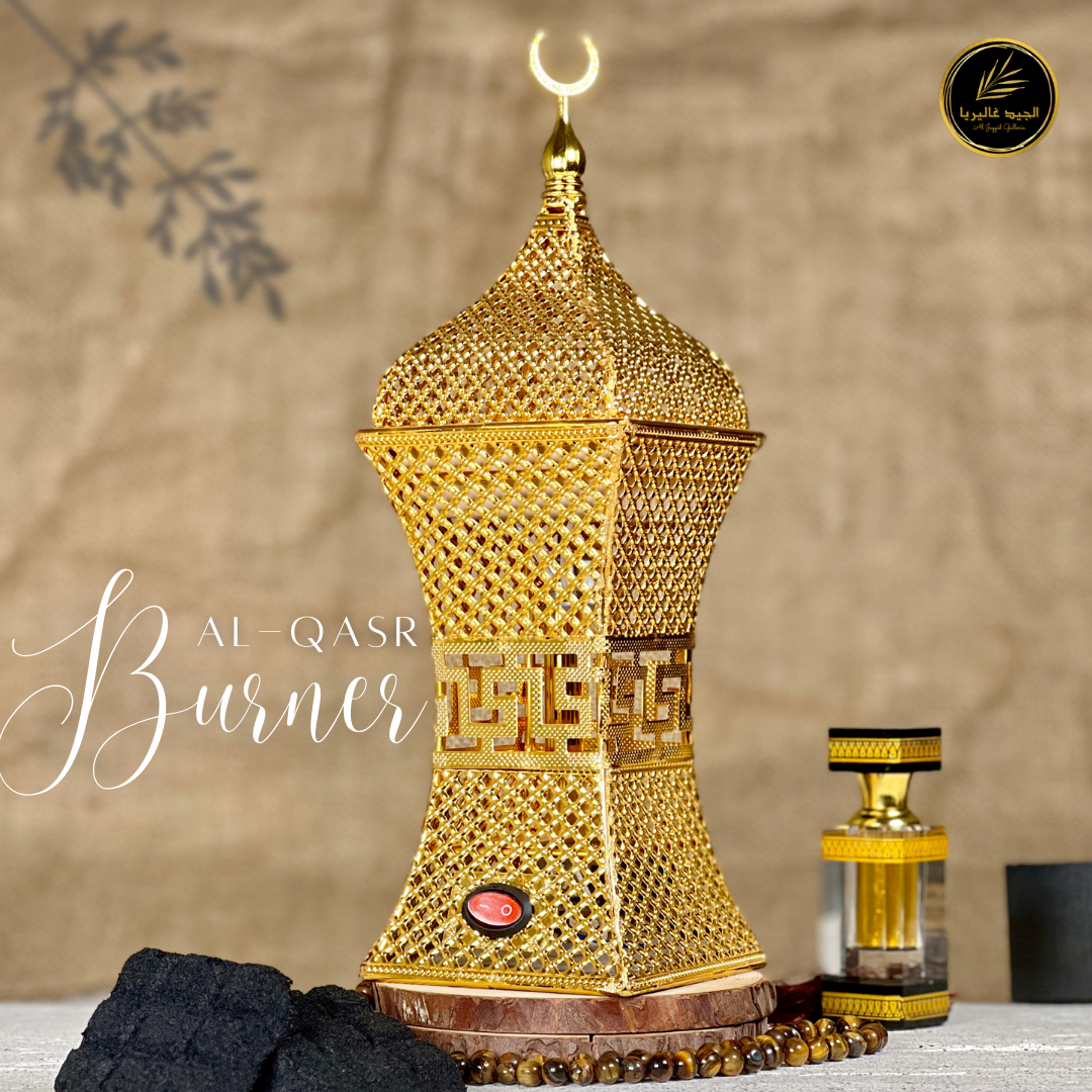 Al-Qasr 'القصر'Bakhoor Burner showing placed on marble surface  with scent bottle & Bakhoors, an elegant design in golden colour.