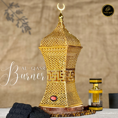 Al-Qasr 'القصر'Bakhoor Burner showing placed on marble surface  with scent bottle & Bakhoors, an elegant design in golden colour.